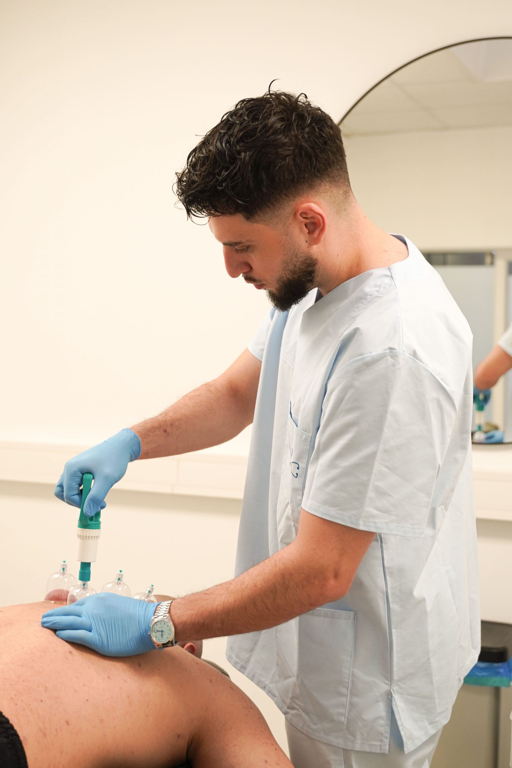 Melih Kandemir führt Schröpftherapie am Rücken eines Patienten durch